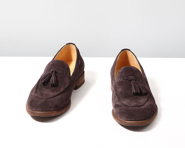 Mocassins à pampilles en daim beige, en daim brun foncé, avec une semelle en caoutchouc cousue et un détail de pampilles à l’avant.