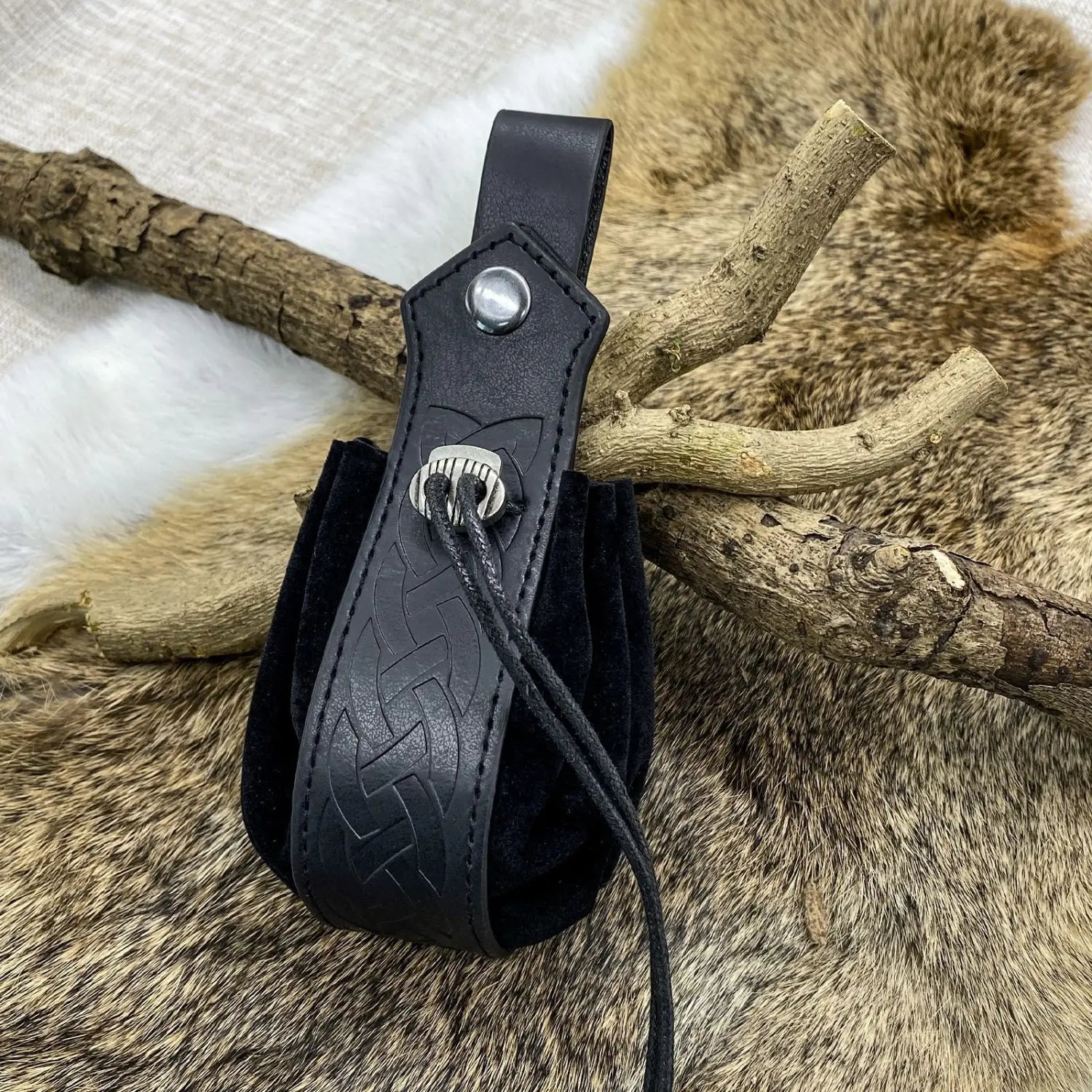 Black leather embossed celtic knot viking sling bag with silver-toned skull clasp and suede-lined interior.