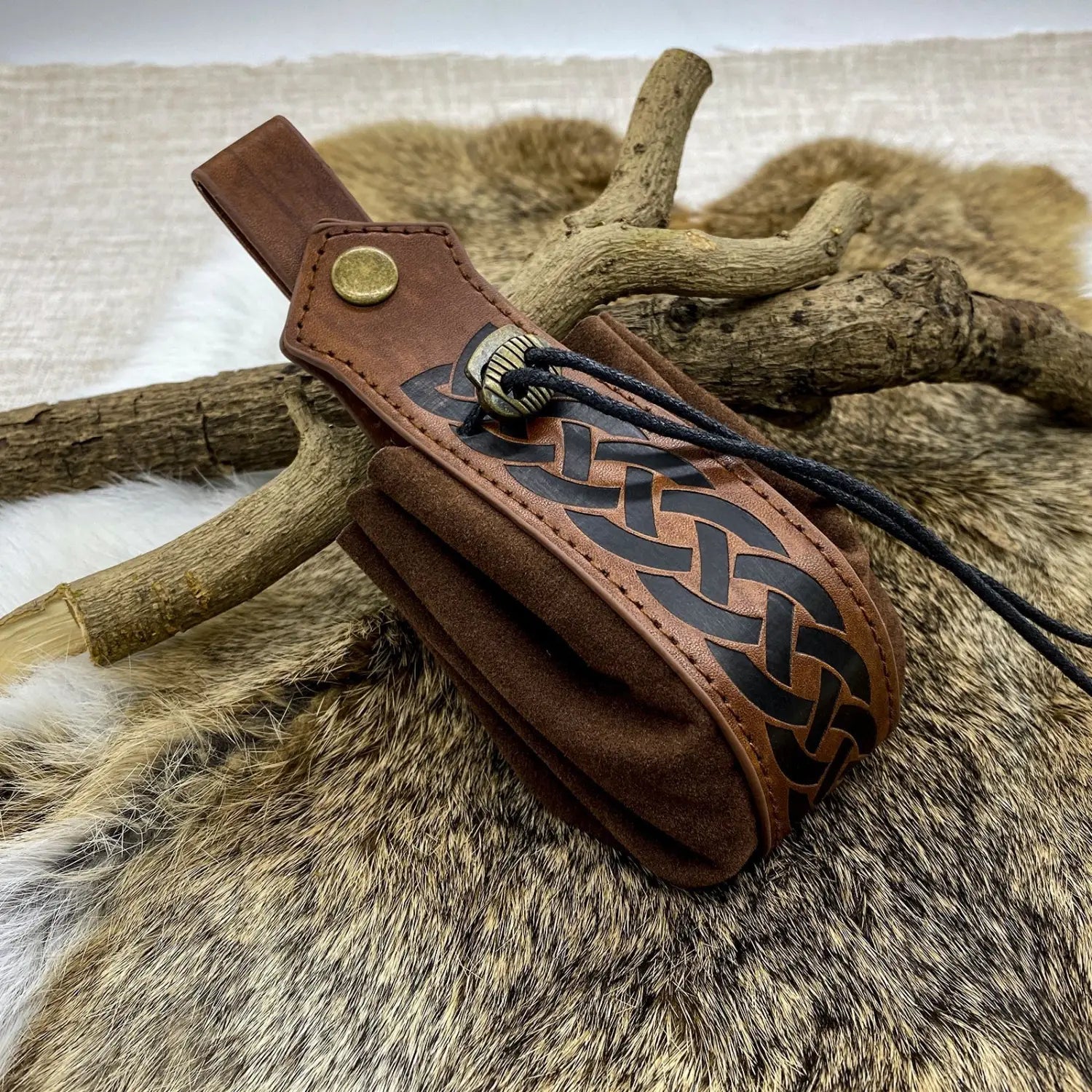 Brown leather embossed celtic knot viking sling bag with black embroidery and metal skull clasp.