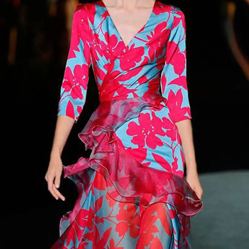 A vibrant pink and turquoise floral tiered maxi dress featuring a v-neckline, three-quarter sleeves, and a layered ruffle skirt.