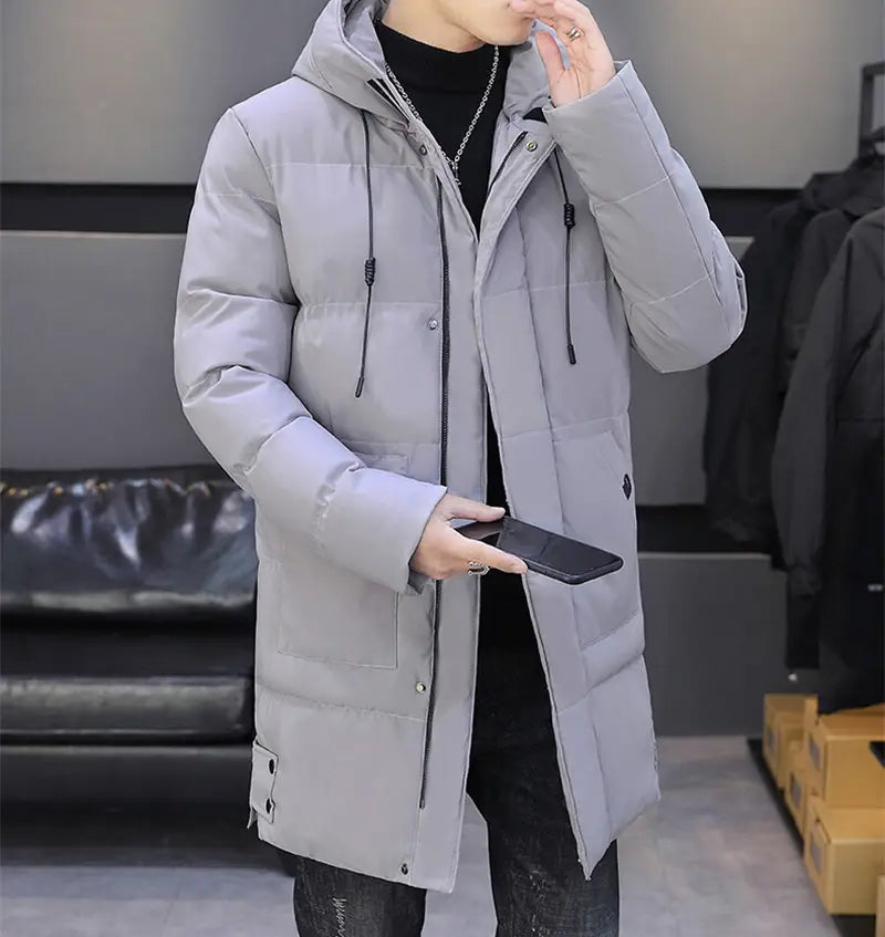 Veste matelassée homme coupe-vent à capuche en gris, avec fermeture à glissière noire et cordons de serrage, conçue pour l’hiver.