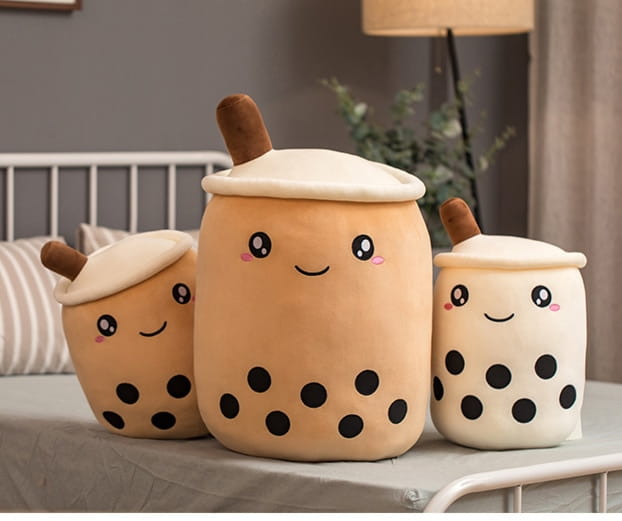 cute beige plush boba tea drink pillows with black tapioca pearls and brown straws designed as soft bubble tea pillow toys.