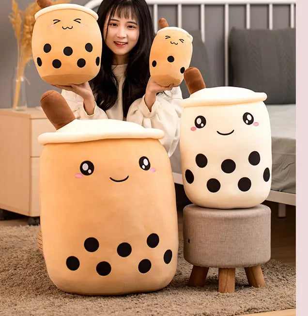 Boba tea plush soft bubble tea pillow toy featuring cute beige and cream-colored fabric with black tapioca pearls embroidered facial features and brown handles.