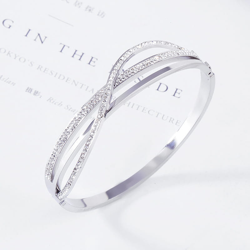 Silver infinity bangle made of titanium steel rose gold featuring a row of sparkling clear crystals along its intertwined bands.
