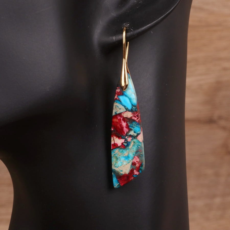 Ein leuchtendes Mosaik aus geometrischem Stein als Tropfen-Ohrring in Form einer Blume mit einer Tropfenform; mit türkisfarbenen und roten ineinander wirbelnden Mustern, eingefasst in einem goldfarbenen Haken.