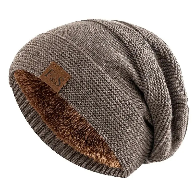 A cozy slouchy gray knit beanie with a plush brown fleece lining and a small leather patch bearing the f&s logo, featured as a fleece lined knitted beanie cap.