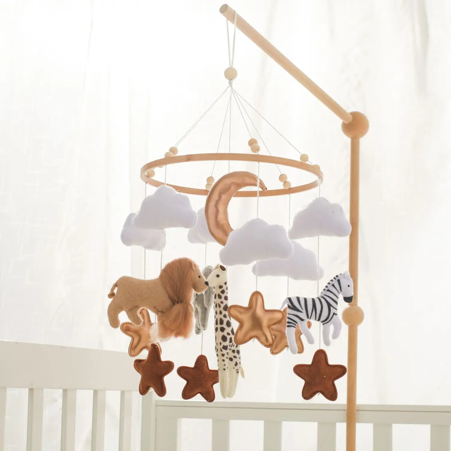 A wooden crib mobile featuring plush safari animals and stars in soft earth tones suspended by strings from a circular frame with felt clouds.