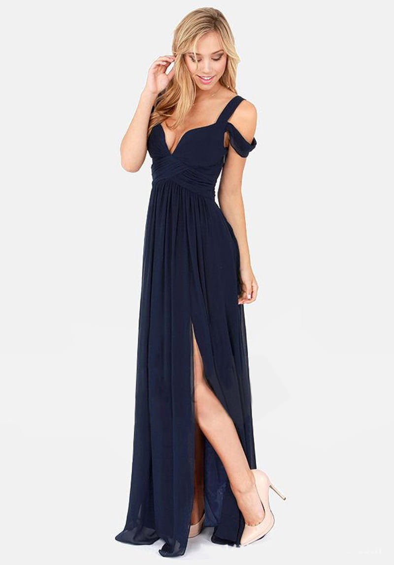 Un vestido maxi plisado floral de gasa azul marino con diseño descubierto en los hombros, escote pronunciado en V y abertura alta.