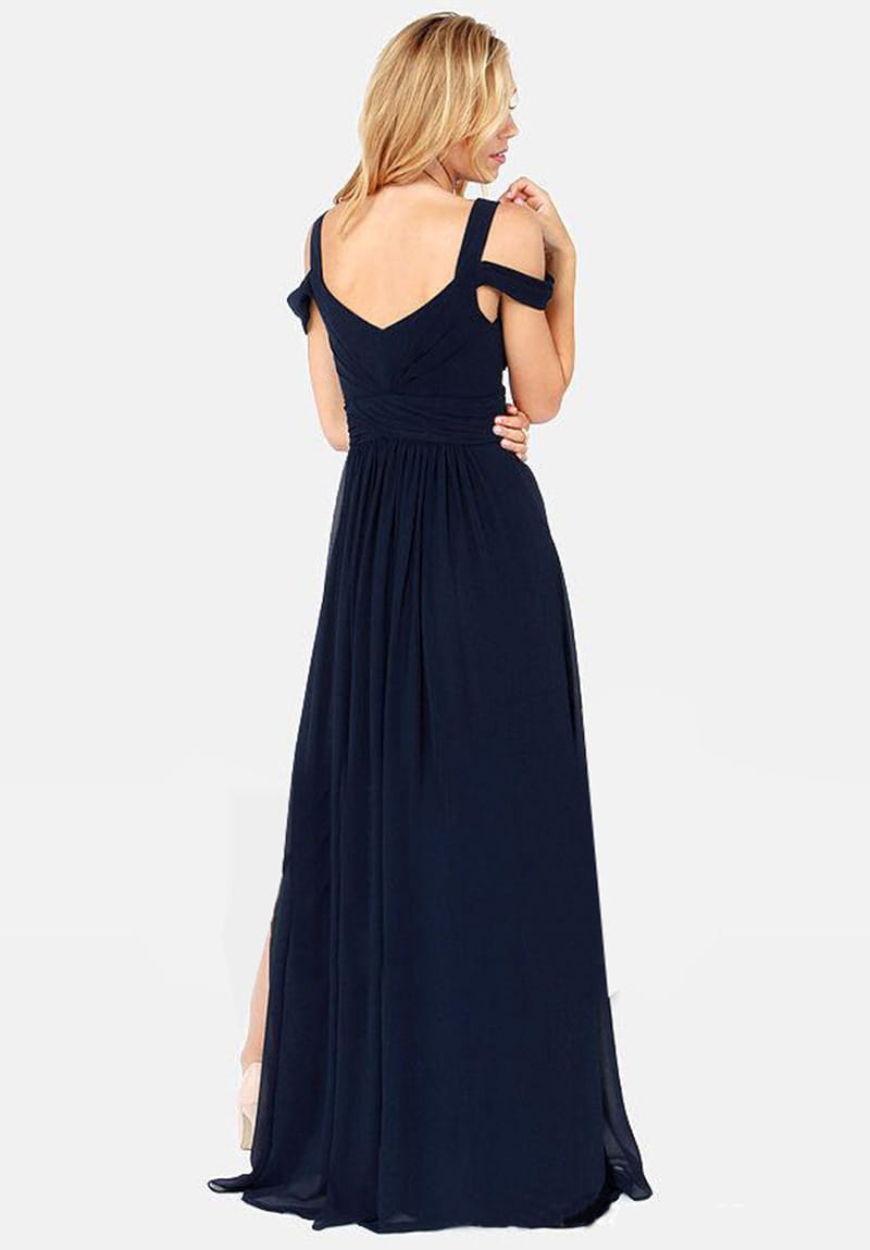 Un vestido maxi plisado floral de gasa azul marino con escote en V, correas tipo lazo descubiertas en los hombros y una abertura alta en un lado.