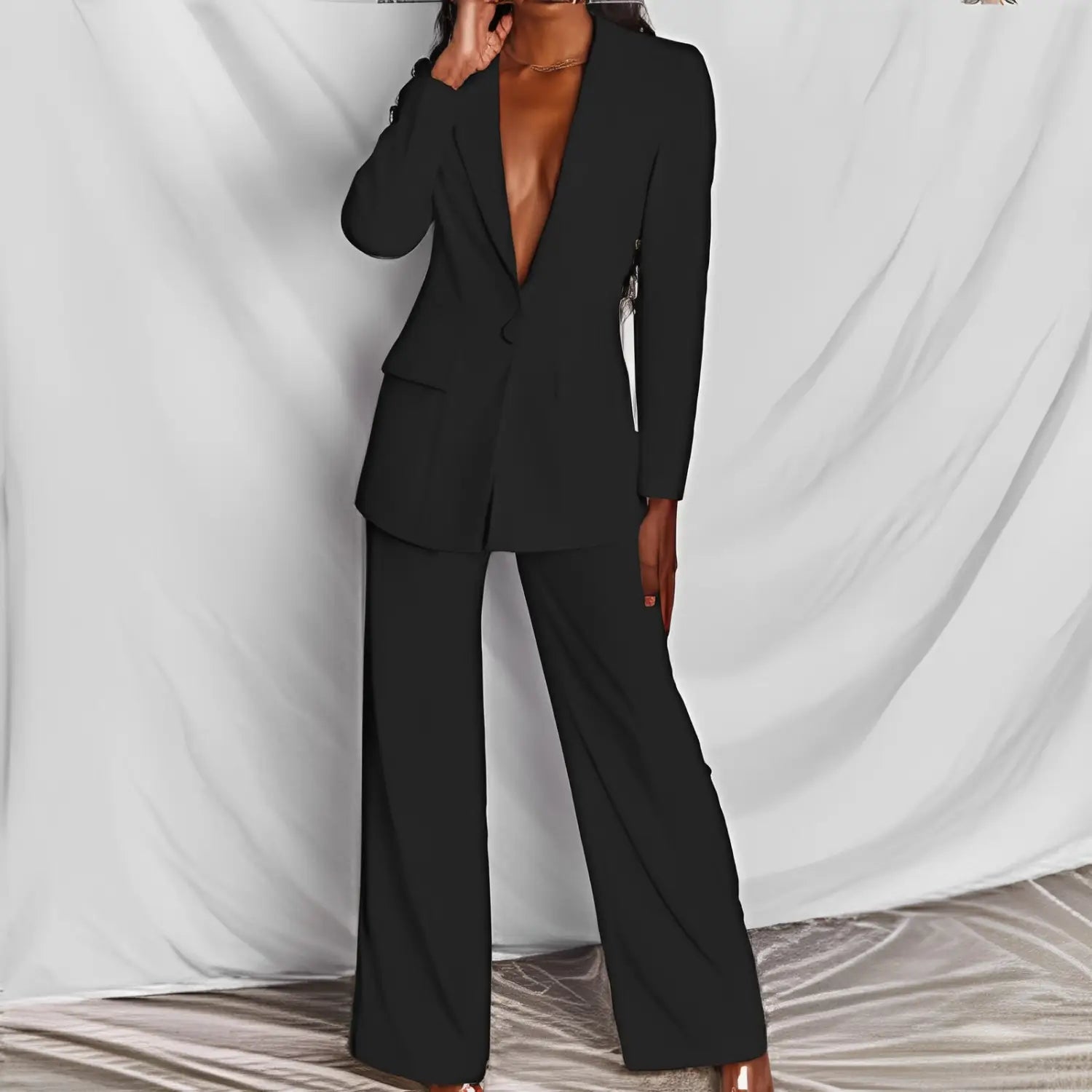Black tailored blazer with a deep v-neckline and long sleeves paired with matching wide-leg trousers in a women’s tailored blazer and wide leg trouser suit set.