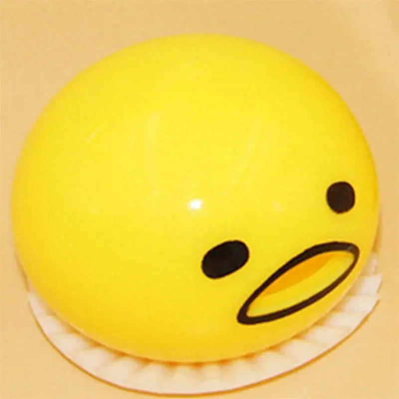 A bright yellow round gudetama-themed stress relief toy with a glossy finish and simple black facial features resembling a vomiting egg yolk.