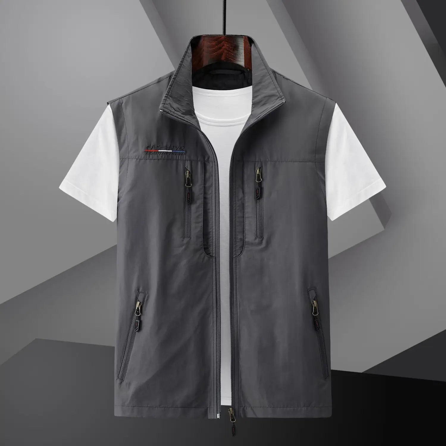 Chaleco utilitario con capucha y múltiples bolsillos para hombre en color gris, con varios bolsillos con cremallera y un logotipo sutil en el lado izquierdo del pecho.