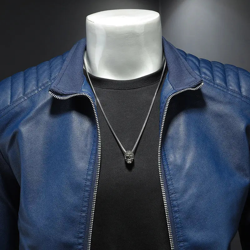 silver skull pendant necklace with a fine chain displayed on a mannequin wearing a blue leather slim fit men’s motorcycle biker jacket.