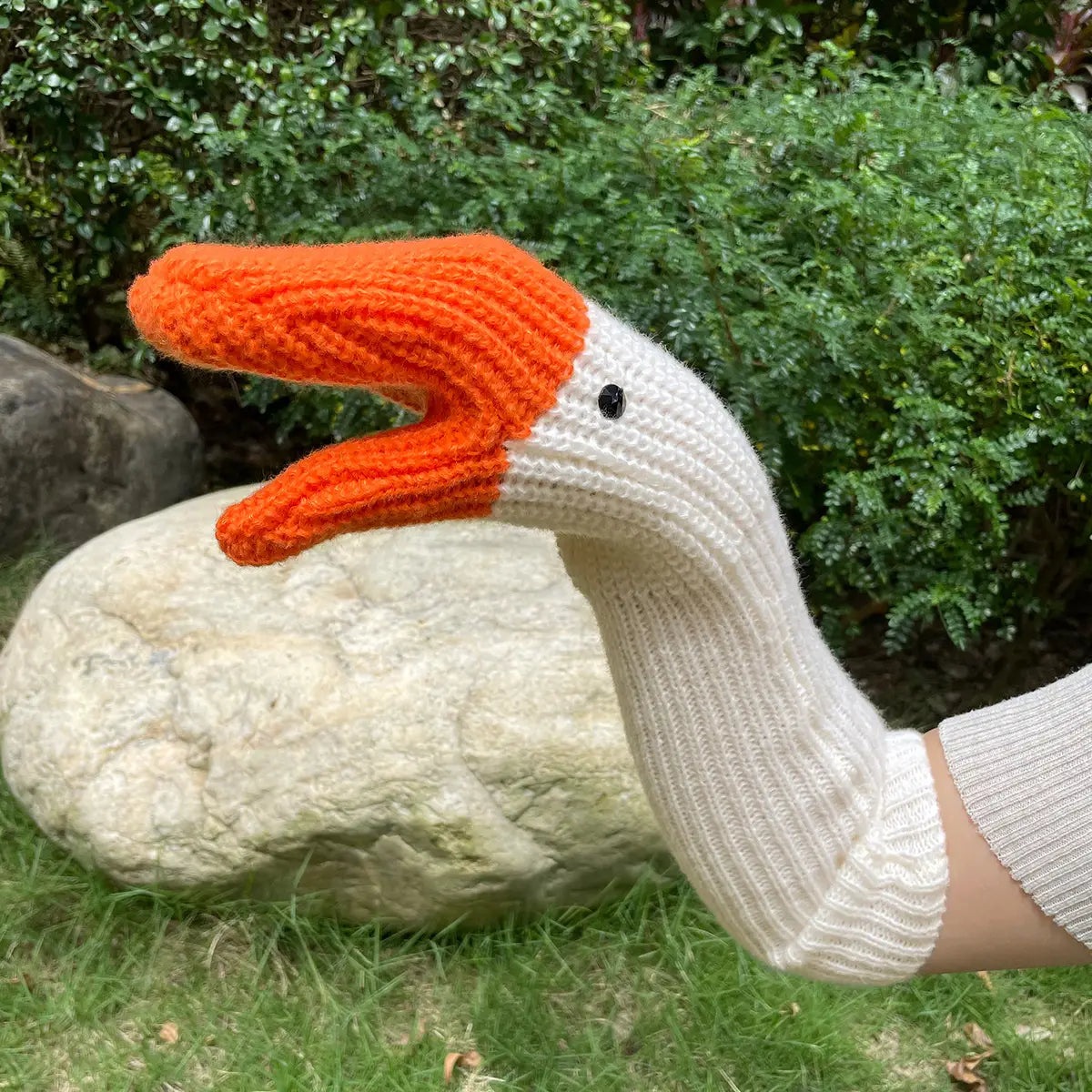Eine gemütliche weiße und orange gestrickte Gänse-Handpuppen-Handschuhkappe mit gerippter Textur, schwarzen Perlenaugen und weichem Garnmaterial, gestaltet als Winter-Handschuhe.