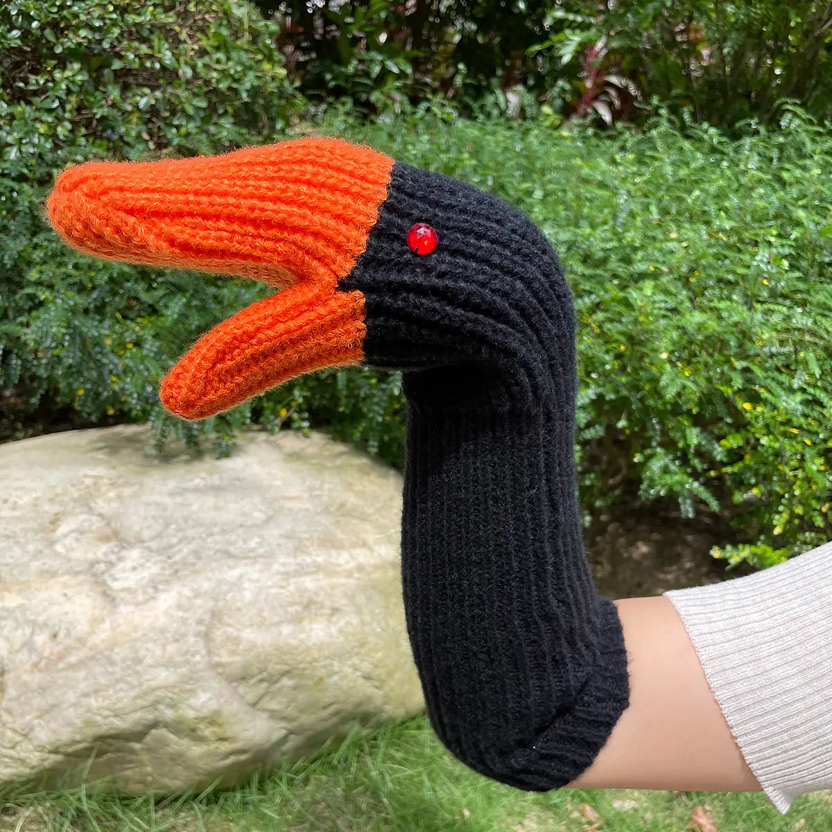 Gestrickte Enten-Handpuppen-Winterhandschuhe mit einem schwarzen und orangefarbenen Entenmotiv und rotem Perlenauge.