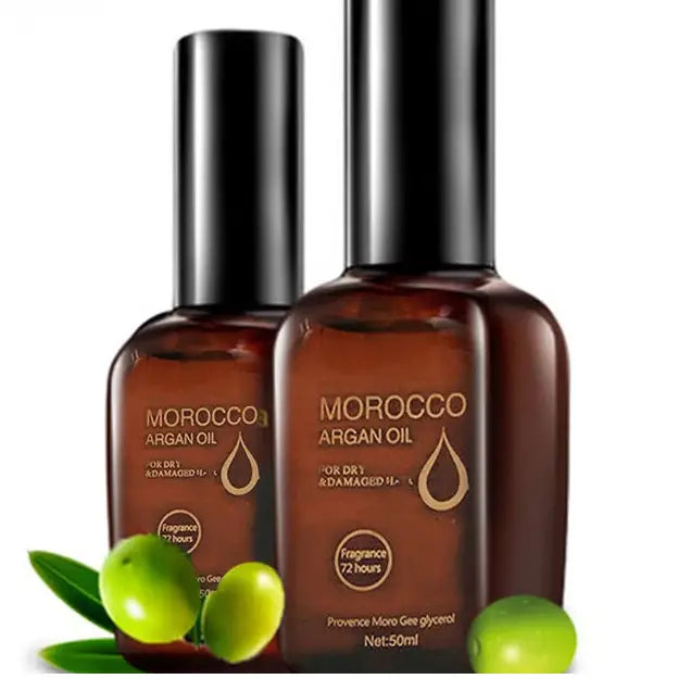 Dos frascos de vidrio ámbar con aceite de argán de Marruecos para el cuidado del cabello seco y dañado, de 50 ml, con tapas negras elegantes y letras doradas junto a frutos verdes frescos de argán.