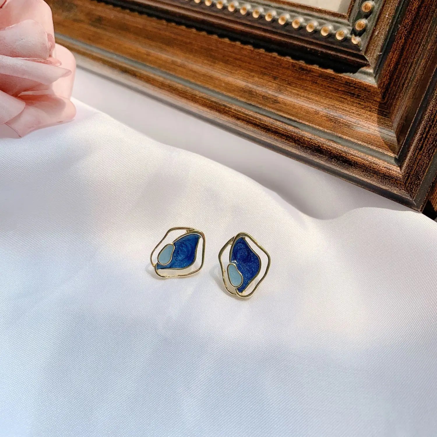 Boucles d’oreilles clous en émail bleu et bleu clair, en argent géométrique, avec des montures irrégulières de ton doré.