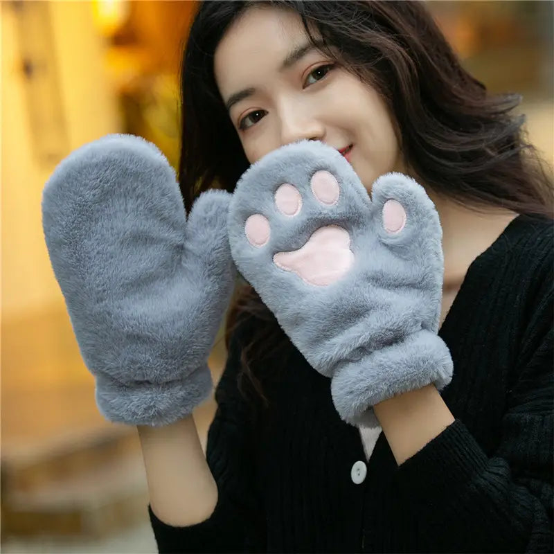 Soft gray fuzzy warm winter mittens with pink cat paw print designs on the palms made of plush material.