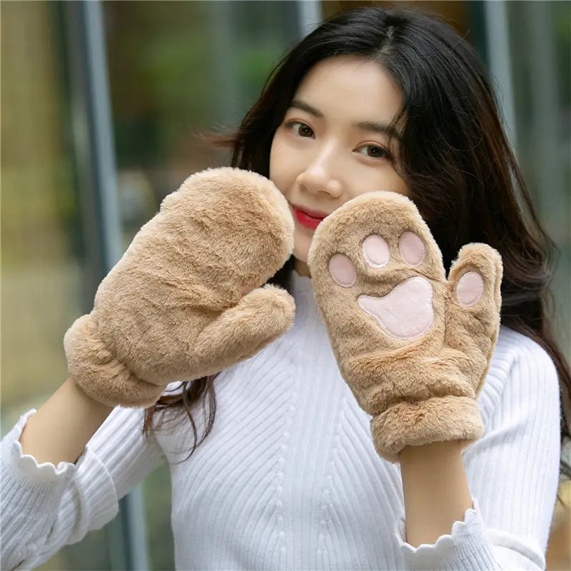 Soft tan fuzzy winter mittens with pink paw print designs on the back made of plush warm material for cold weather use.