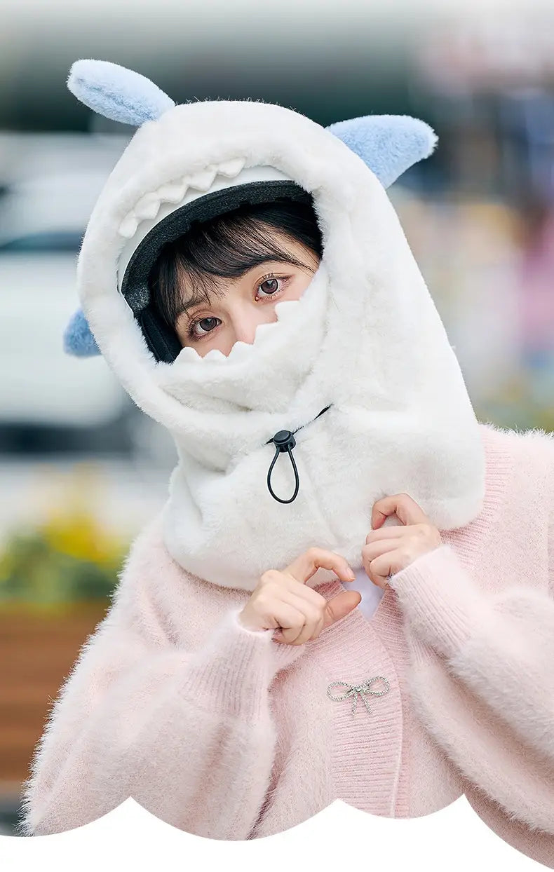 Écharpe à capuche moelleuse blanche en forme de requin, avec des oreilles bleu clair et une fermeture à cordon de serrage noir, conçue comme un bonnet d’hiver pour la protection des oreilles.