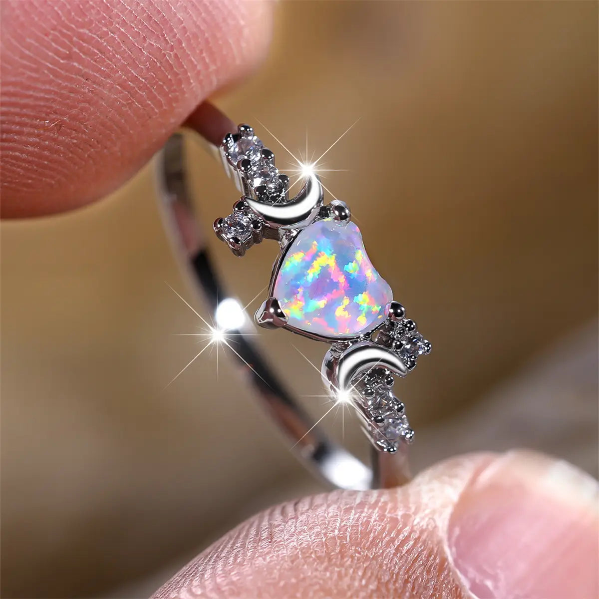 A delicate silver heart opal crescent moon ring featuring a central iridescent opal stone flanked by crescent moon motifs and sparkling clear diamonds.