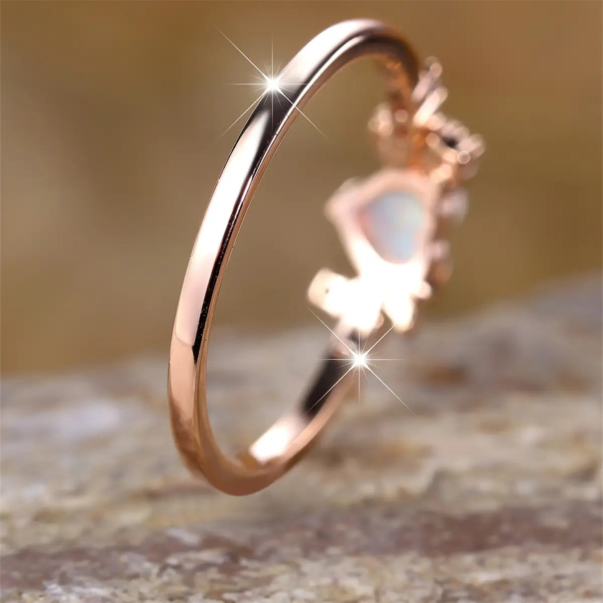 A delicate rose gold heart opal crescent moon ring featuring a central opal stone set in an ornate crown like design with diamonds.