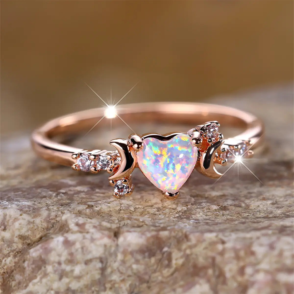 A rose gold heart opal crescent moon ring with clear cubic zirconia stones set around a heart-shaped opal center.