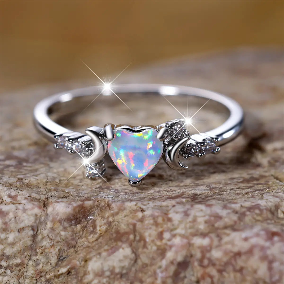 A delicate silver heart opal crescent moon ring with iridescent blue pink and white flashes and clear crystal diamond accents.