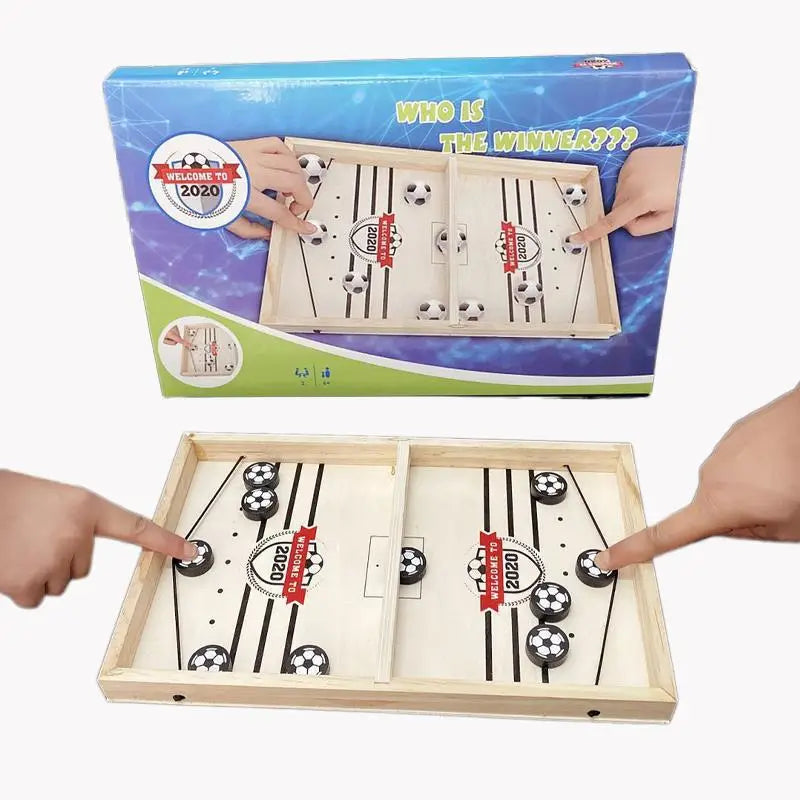 Juego de percutor lanzador tipo sling de madera sobre mesa que presenta discos tipo balón en blanco y negro sobre una superficie de color claro con la marca «Welcome to 2020».