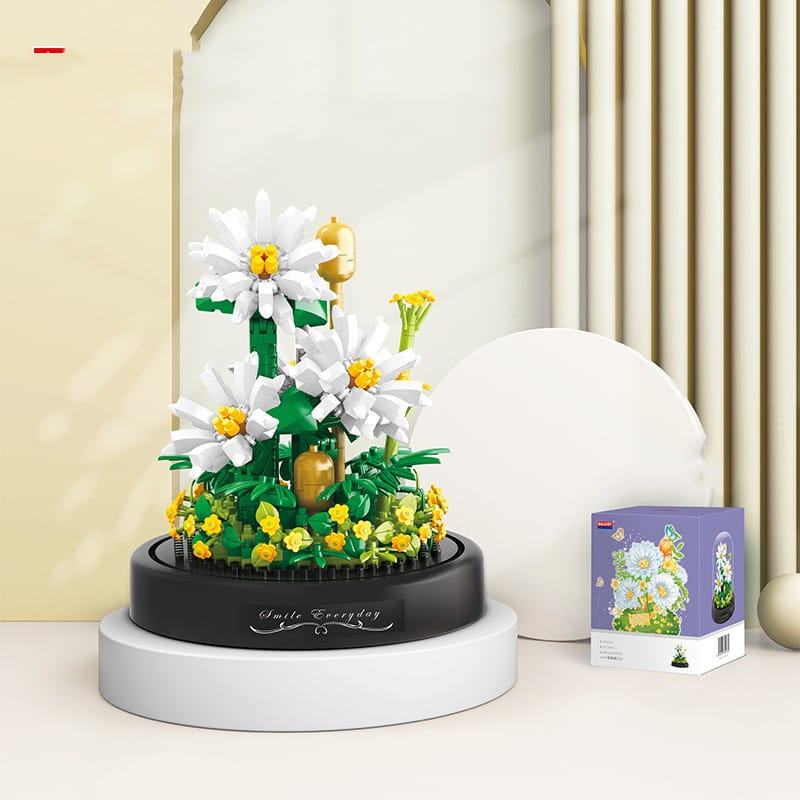 Un ramillete de piezas de construcción florales que presenta flores estilo lego de margarita blancas y amarillas con tallos verdes, mostradas sobre una base circular negra, con la inscripción «smile everyday».