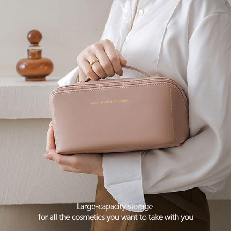 A soft blush pink leather large capacity travel makeup bag organizer with a top handle and subtle gold lettering on the front.