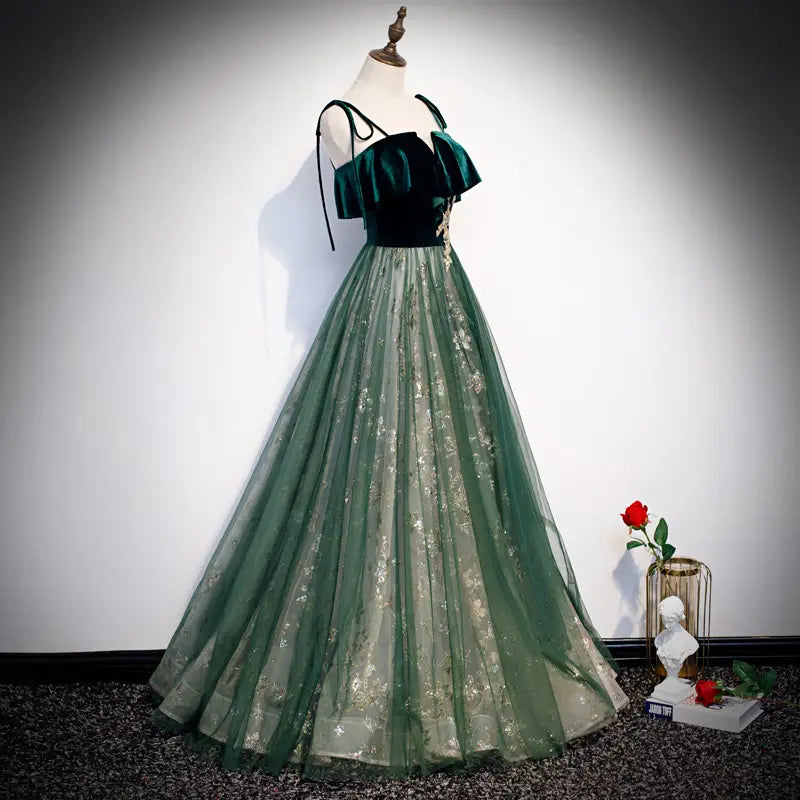 Robe émeraude en velours à épaules dénudées, avec une jupe en tulle fluide et une délicate broderie dorée.