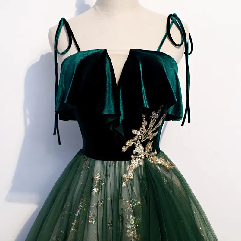 Robe émeraude en velours à épaules dénudées, avec des ornements floraux en perles dorées et une jupe en tulle transparent.