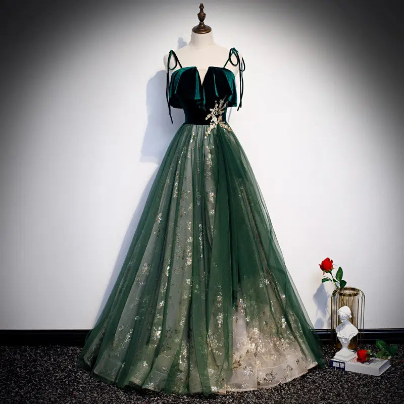 Robe émeraude en velours à épaules dénudées, avec une broderie florale dorée sur le tissu en velours et en tulle.