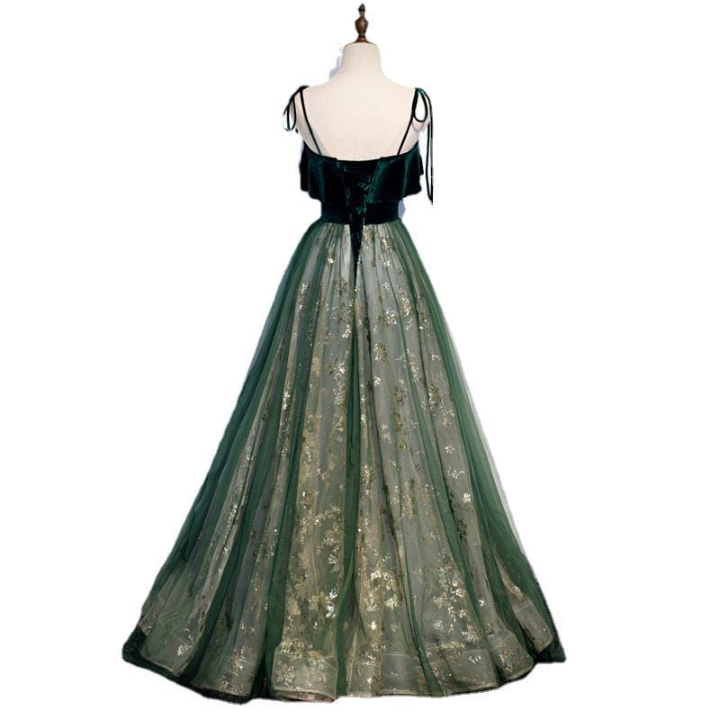 Robe émeraude en velours à épaules dénudées, dotée d’un corsage en velours vert avec des bretelles noires à nouer et d’une jupe en tulle transparent ornée d’une broderie florale dorée.