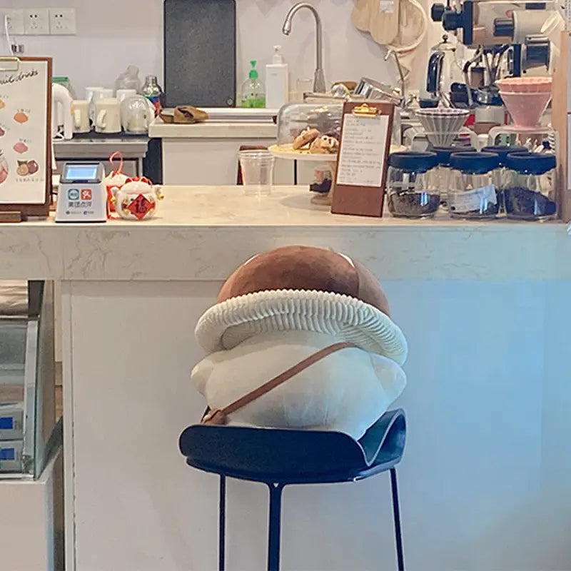 A plush beige and white corduroy bread-shaped cushion with a textured ribbed edge sits on a blue bar stool as a mushroom plush pillow doll toy.