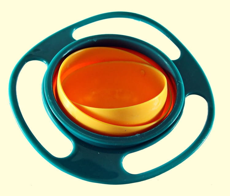 Tazón para alimentación de bebé a prueba de derrames con rotación universal de 360 grados en plástico verde azulado, con tazones interiores en naranja y amarillo, diseñado para una alimentación segura y conveniente.