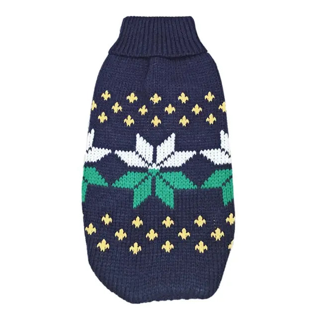 Navy blue knitted dog sweater with white and green floral pattern and gold fleur-de-lis motifs designed as festive winter apparel.