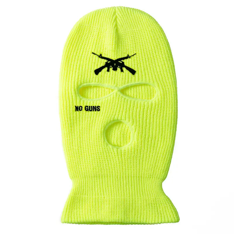 A neon yellow knitted ski mask balaclava with black embroidered crossed guns and no guns text designed as a windproof hat for cold weather use.