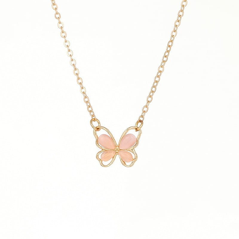 Un delicado collar con dije de mariposa con baño de oro, con alas de esmalte rosa suave y una gema translúcida.