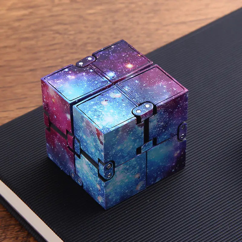 A cosmic galaxy-themed infinity cube fidget toy for stress relief and ADHD featuring vibrant purple blue and pink nebula design on interlocking plastic panels.