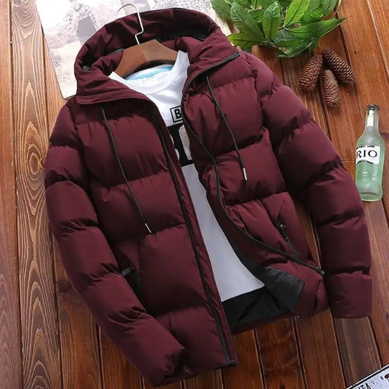 Men’s quilted cotton hooded puffer jacket in maroon with black drawstrings and zipper accents hanging on a wooden hanger.