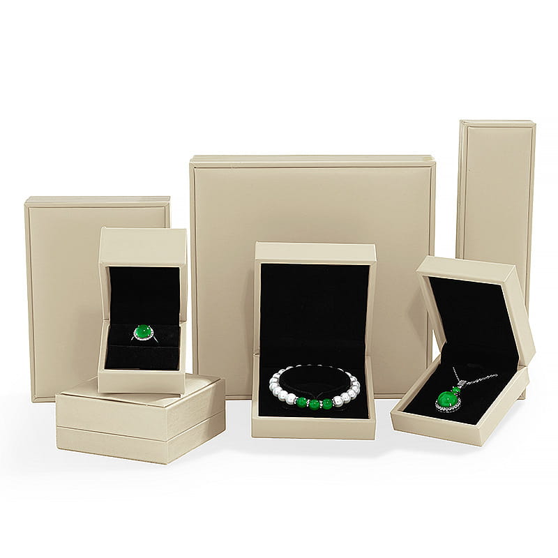 beige luxury jewelry display boxes with black velvet interiors showcasing sterling silver interlocking infinity heart pendant necklaces featuring green gemstones