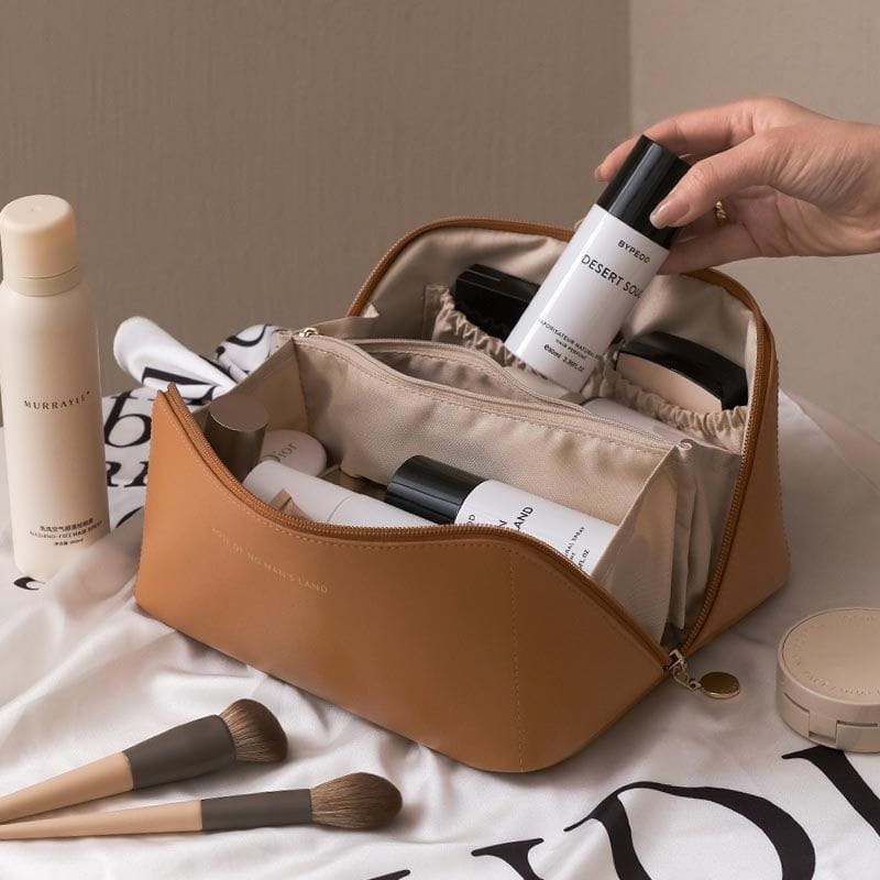 Große Reisekosmetiktasche aus PU-Leder in Cognacfarbe mit beigem Innenfutter und goldfarbener Reißverschlusszuglasche.