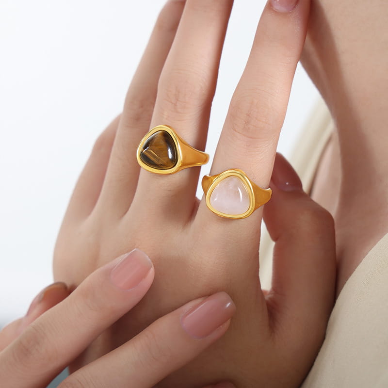 Gold signet rings with triangular faceted amber and pale pink gemstones set in a sleek polished titanium steel band.