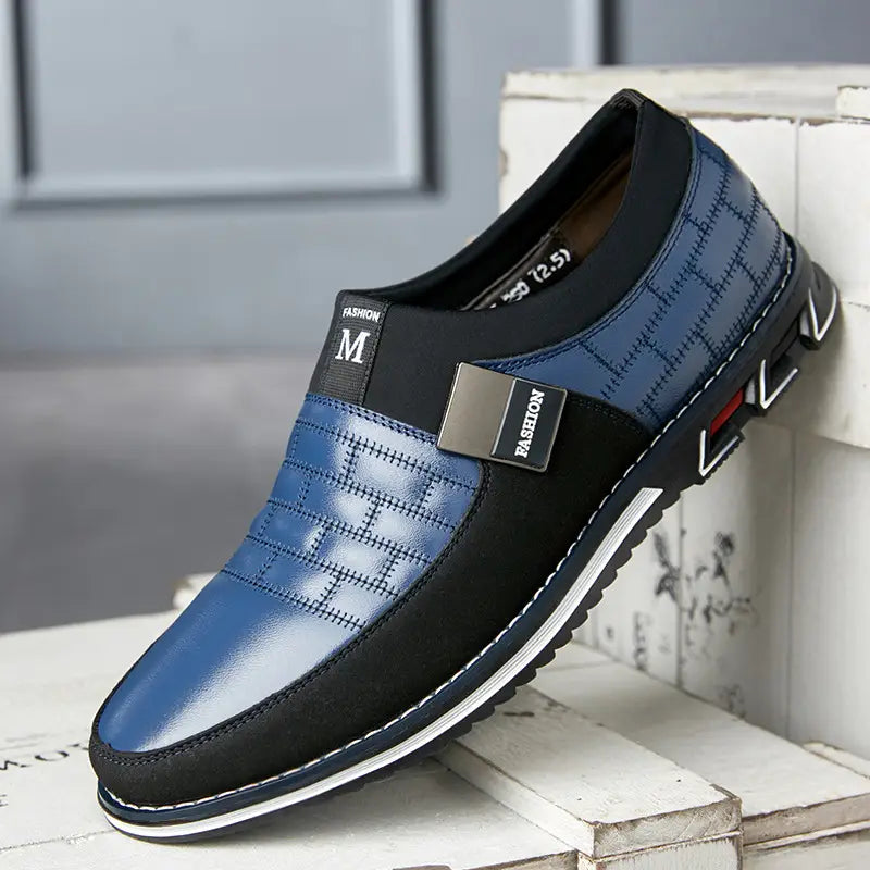 Men’s casual leather slip-on shoe in blue and black with quilted pattern, stitched detailing, and metallic branding accents, available in large sizes.