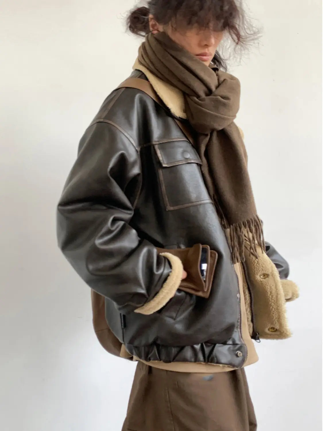 Maillard leather bomber jacket in dark brown featuring tan shearling lining and front pockets.