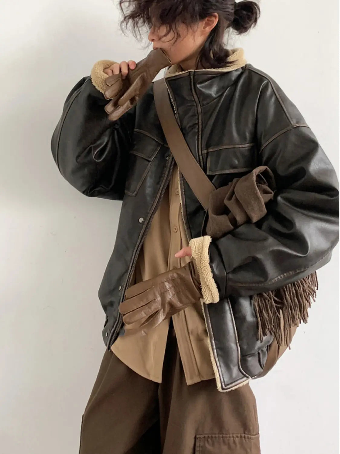 Dark brown leather maillard bomber jacket with shearling lining and fringed sleeve detail.