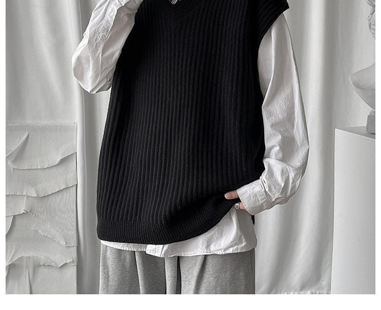 Schwarze gerippte Strickweste ohne Ärmel, getragen über einem weißen Langarmhemd – Herren-Plusgröße V-Ausschnitt-Strickweste ohne Ärmel.