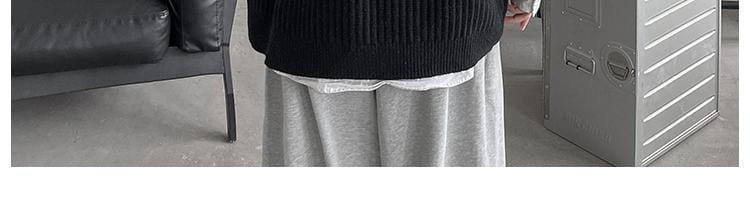 Herren-Plusgröße V-Ausschnitt-Strickweste ohne Ärmel in Schwarz, gerippt gestrickt, mit dezentem weißem Zierbesatz am Saum.